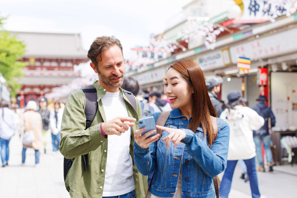 観光地でスマホを見ながら話す外国人男性と日本人女性